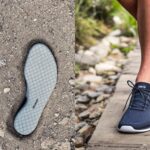 A pair of gray insoles with a diamond pattern lies on dirt, shown on the left. On the right, a person in dark blue barefoot shoes with "Xero" branding walks on a wooden path outdoors.